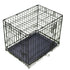 Black metal dog crate on a grassy background