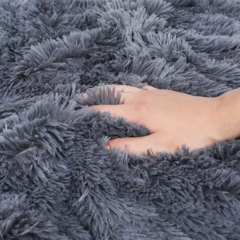 Hand touching a fluffy gray rug