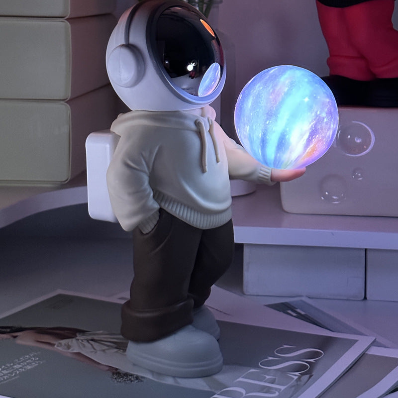 Holding a dreamy starry sky beige top + brown pants Creative Astronaut Bluetooth Speaker with 3D Starry Sky Lighting, Portable Wireless Moon Lamp Speaker -Perfect Gift for Space Enthusiasts